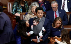Rep. Alexandria Ocasio-Cortez (D-N.Y.) talks to the infant child of Rep. Jimmy Gomez (D-Calif.) in the House Chamber at the Capitol on Jan. 3. (Evelyn Hockstein/Reuters)